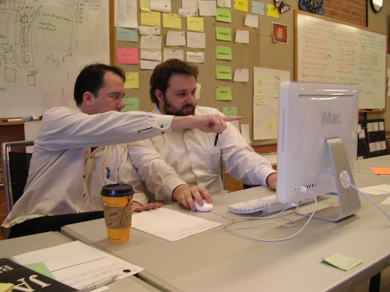 IT team resilience in practice: two engineers sharing one screen so system knowledge is not locked in a single head